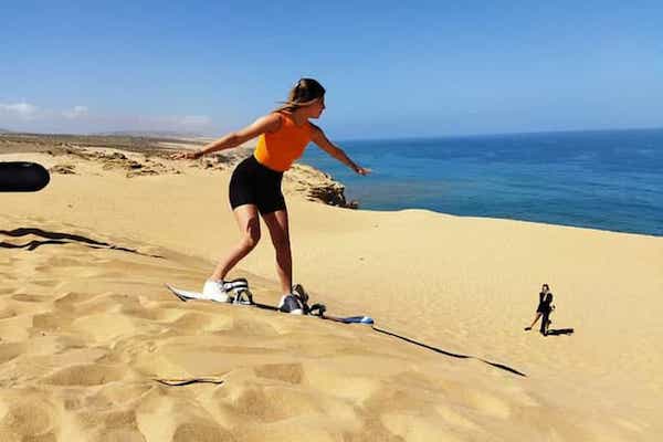 Golden sand dunes of Timlalin with visitors sandboarding near Agadir.