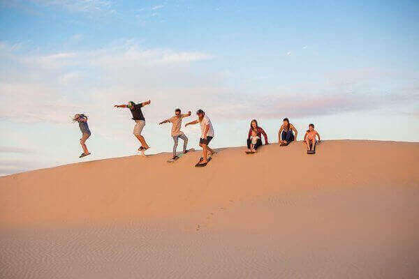 Sandboarding on the golden Timlalin Dunes near Agadir with stunning Atlantic Ocean views in Morocco