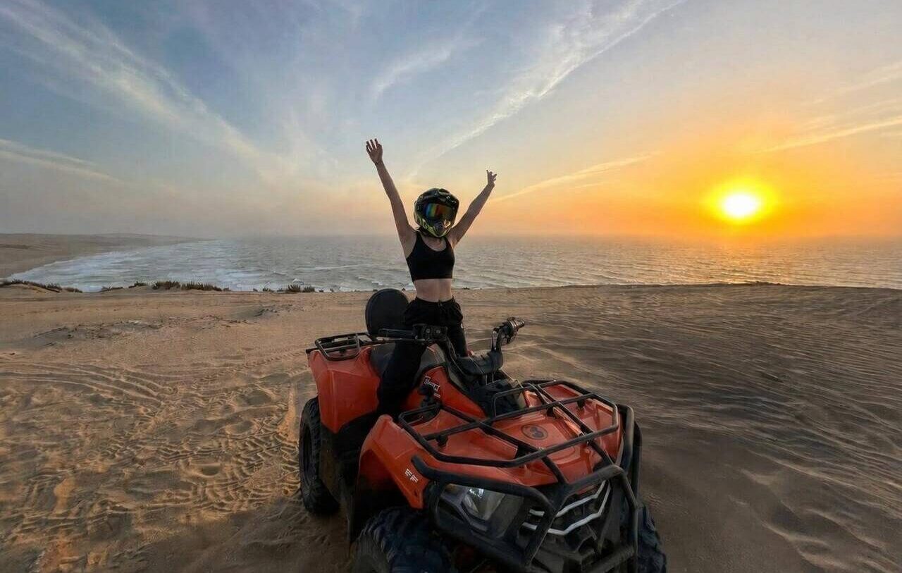 ATV quad bike crossing the golden sand dunes of Timlalalin near Agadir with Atlantic Ocean views.