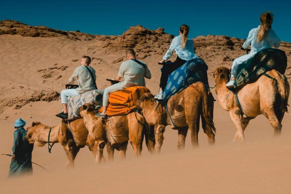 Family riding camels across the Timlalin sand dunes near Agadir.