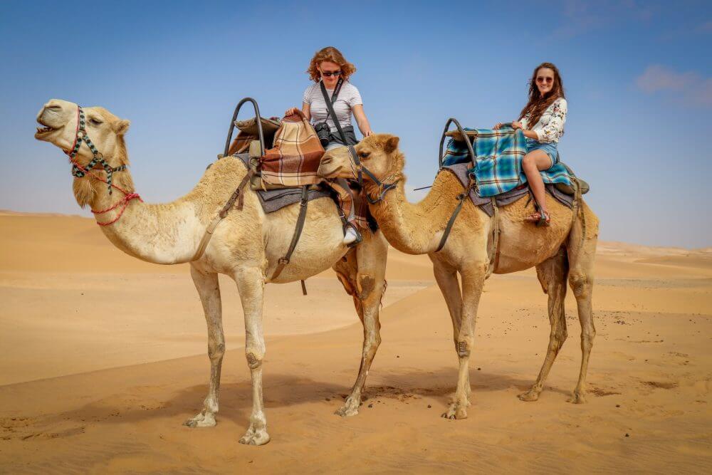 Tourist taking photos during a camel ride in Timlalin near Agadir.